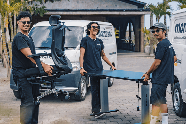 The Monis crew carrying an office chair and a standing desk to a customer's villa